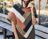 Mujer con un poncho de ganchillo a rayas en tonos tierra, azul marino y blanco. El patrón poncho es ideal para el otoño.