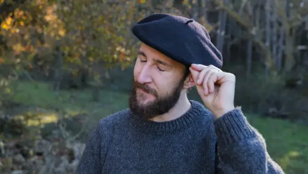 Hombre con barba ajustando su boina de lana, ideal para aprender como hacer una boina de lana.